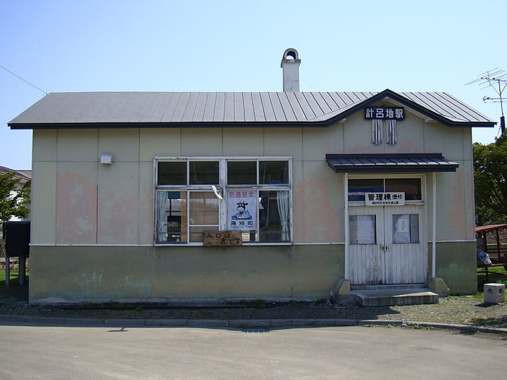 A photo of Kerochi Station, an abandoned train station in Hokkaido. A small building with a brown roof and white doors.